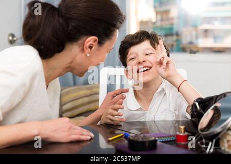Portrait of happy tweenager having friendly chat with his mom at home Stock Photo