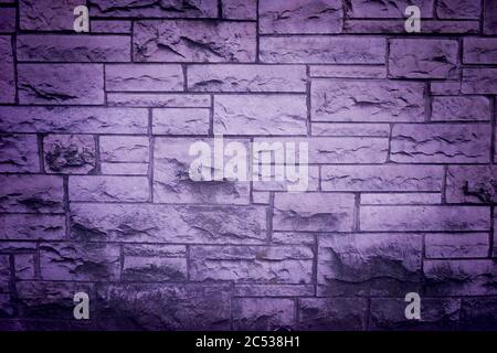 Purple tinted brick wall with grunge effect, vignette and natural texture. Stock Photo