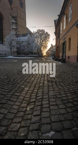 Shot of a small old plaza in Romania  with short buildings and ground and trees partly in snow Stock Photo