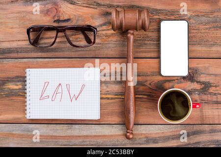 Minimal workspace mobile phone gavel cup of coffee on wood table. Stock Photo