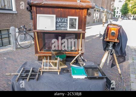 Amsterdam, Netherlands - July 19, 2018: Street photographer is taking pictures of tourists using old analog camera. High quality photo Stock Photo