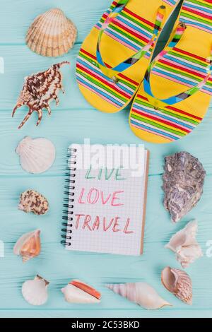 Different sea shells and yellow sandals in the corner on turquoise background. Stock Photo