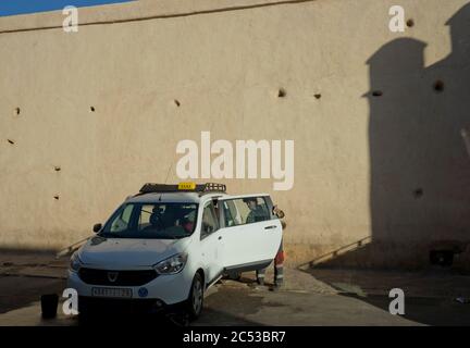 Taxi driver cleaning his car the the wall ramparts of the medina old town in Marrakesh,Morocco Stock Photo