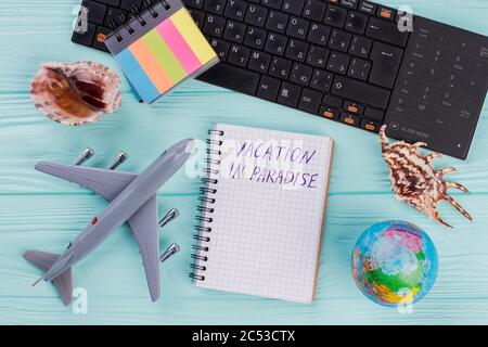 Tourist stuff with notebook, toy airplane, seashell, globe on blue background. Stock Photo