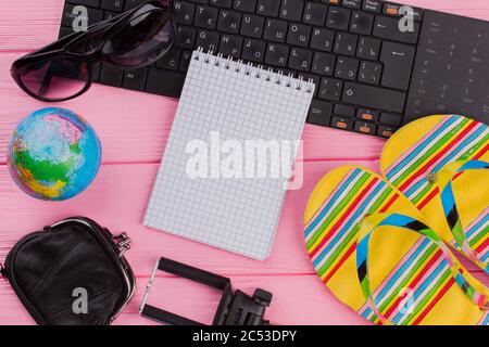 Blank notebook with woman's traveler accessories glasses wallet and flip-flops on pink table top background. Stock Photo