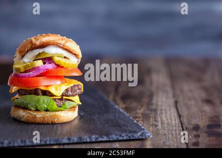 A big, fat, juicy double cheeseburger made with two 100% beef patties, slices of melted cheese, onions, pickles, lettuce, tomatoes, and mayo on a fres Stock Photo