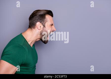 Profile photo of attractive crazy guy neat hairdo bristle yelling furious side empty space fighting with girlfriend nervous bad mood wear casual green Stock Photo