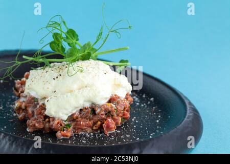 Portion of appetizer tartar made from chopped fresh beef, parmesan cheese mousse Stock Photo