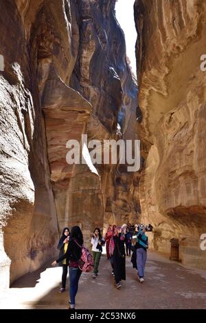 PETRA, JORDAN - APR 2, 2015: Tourists walking in Siq canyon in Petra. Petra's temples, tombs, theaters and other buildings are scattered over 400 squa Stock Photo
