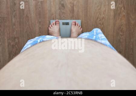 Fat man standing on scales, huge belly, top view Stock Photo