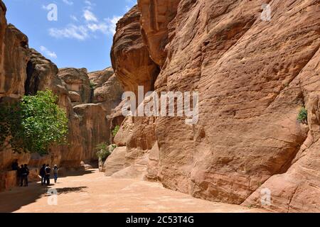PETRA, JORDAN - APR 2, 2015: Tourists walking in Siq canyon in Petra. Petra's temples, tombs, theaters and other buildings are scattered over 400 squa Stock Photo