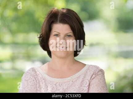 Portrait of middle aged woman with dark hair on nature Stock Photo
