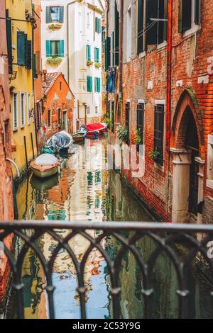 Venice, Italy. Narrow channel street and colored houses with local boats in Venezia. Stock Photo