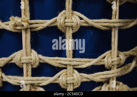 Closeup shot of thin ropes tied in nautical knots against a royal blue background fabric Stock Photo