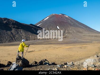 Young boy in bright yellow raincoat looking at Mt Ngauruhoe (aka Mt Doom) in New Zealand’s Tongariro national park Stock Photo