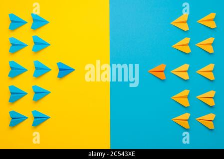 Paper airplanes teamed up in 2 colors, blue and yellow, face to face in battle formation. A confrontation between two teams, leading the team concept. Stock Photo