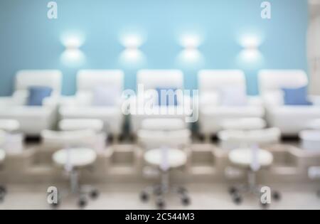 Nail salon interior as creative abstract blur background. Pedicure armchairs in a modern salon. Inside a beauty studio with white and blue design. Row Stock Photo