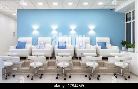 Moscow – Feb 7, 2019: Pedicure armchairs in a modern salon. Inside a beauty studio with white and blue design. Row of chairs in spa. Nail salon bright Stock Photo