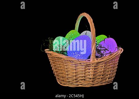 glowing Easter eggs in wicker basket with grass isolated on black Stock Photo