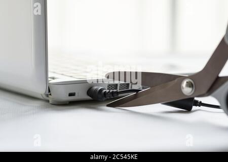 Charging cord of a laptop between the scissors' blades Stock Photo