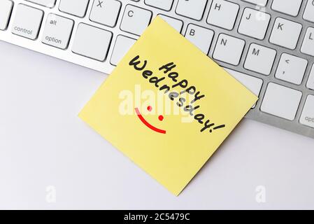Happy Wednesday text on yellow paper note stick on computer keyboard Stock Photo