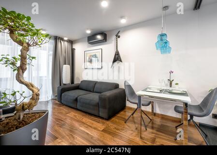 Moscow - March 25, 2018: Modern home interior with couch, table and plants. Beautiful minimalist interior design of living room with white walls. Luxu Stock Photo