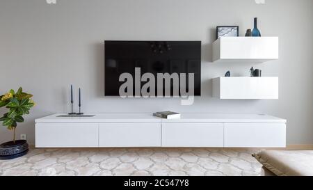 Moscow - June 18, 2018: Modern home interior with TV and flower. Light interior design of living room. Panoramic view of the stylish minimalist white Stock Photo