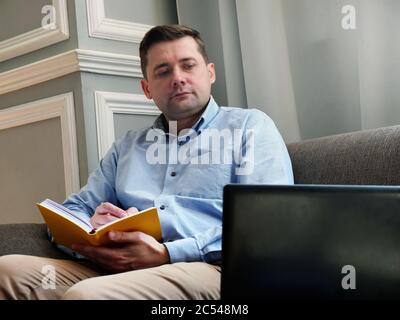 Work from home. A man checks the data and works while sitting on the couch. Stock Photo