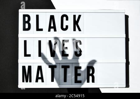 BLACK LIVES MATTER text with deep shadows of hand on a black and white background. Protest against the end of racism, anti-racism, equality Stock Photo