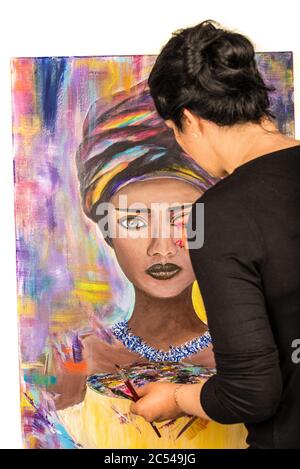 Brunette woman painting portrait of african woman on canvas against white background Stock Photo
