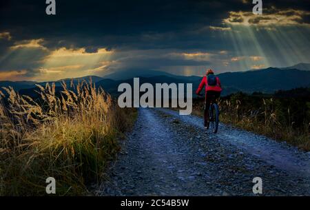 Cycling woman riding on bike in autumn mountains forest landscape. Woman cycling MTB gravel road trail track. Outdoor sport activity. Stock Photo