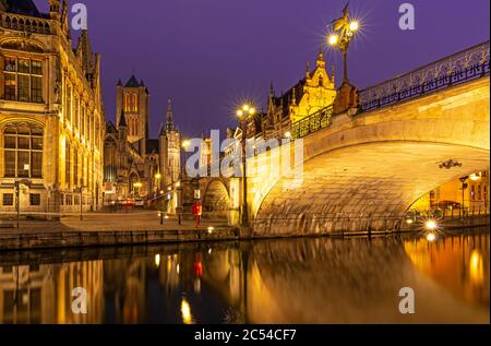 The Saint Michael Bridge and the belfry tower of Gent (Ghent) with a reflection in the Leie river by the Graslei at night, East Flanders, Belgium. Stock Photo