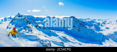 Ski in winter season, mountains and ski touring man on the top in sunny day in France, Alps above the clouds. Stock Photo