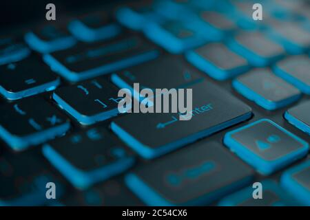 Blue backlit computer keyboard macro shot of enter key Stock Photo