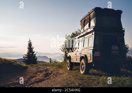 Off-road 4x4 with pop top elevating roof sleeping tent storage vehicle on the dirty country road in the Slovakian mountains in the early morning sunri Stock Photo