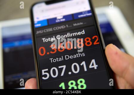 Viersen, Germany - June 30. 2020: Close up of mobile phone screen hold by male hand with counter of John Hopkins university showing numbers of worldwi Stock Photo