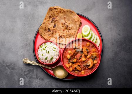Mushroom sabzi in tomato curry with chickpea and spinach, Indian main course menu served with Paratha and cooked white rice Stock Photo