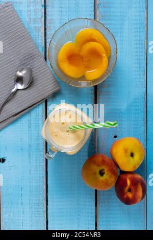 Fresh ripe peaches, natural peach juice in a mason jar, and canned peaches in a glass bowl Stock Photo