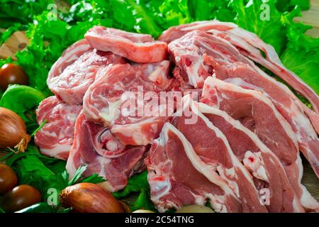 Raw lamb cutlets on wooden cutting board with parsley and vegetables Stock Photo
