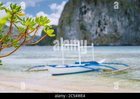 El Nido. Defocused traditional filippino boat on shore with Pinagbuyutan island in background. Palawan, Bacuit archipelago, Philippines. Stock Photo