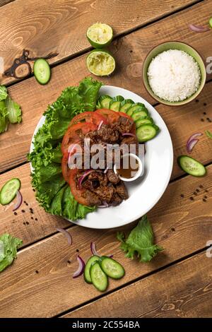 Bo Luc Lac in portrait orientation. Also named Lok Lak in cambodia or Shaking Beef in America. Tasty marinated sauteed beef cubes are served with fres Stock Photo