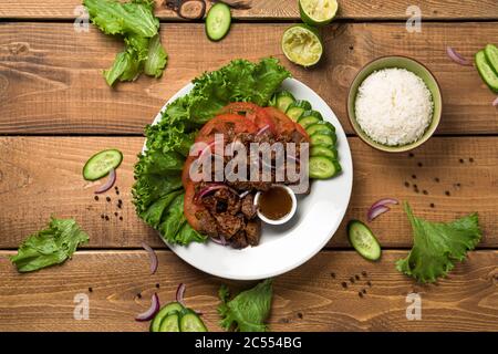 Bo Luc Lac flat lay from above view. Also named Lok Lak in cambodia or Shaking Beef in America. Tasty marinated sauteed beef cubes are served with fre Stock Photo