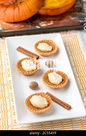 Sugary butter tart treats. Mini sugar pies (or butter tarts) with a crisp pastry crust, a sweet filling and pumpkin spice whipped cream on top. A tast Stock Photo