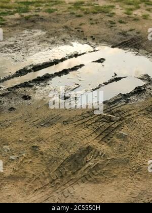 Puddles in rainy day. Muddy field, dirt road after rain. Puddle and mud with tire track texture. Impassibility Of Roads. Helplessness concept Stock Photo