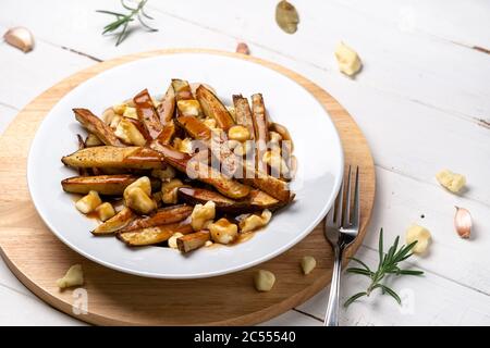 Montreal Poutine gravy fries dish. A classic fast food cuisine dish from Quebec. This canadian comfort food is made with french fries mixed with tasty Stock Photo