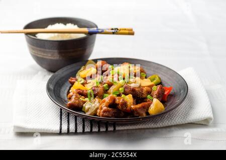 Sweet and sour pork with rice bowl. Deep fried meat is added to stir fried pineapple, onions, peppers and sauce. Sweet and sour dishes are common in a Stock Photo