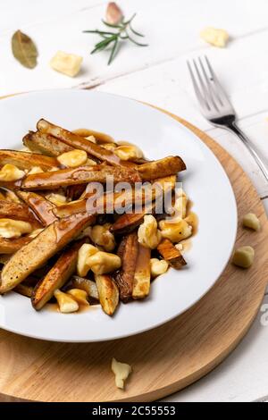 Poutine vertical portrait view. A classic fast food cuisine dish from Quebec. This canadian junk food is made with french fries mixed with tasty chees Stock Photo