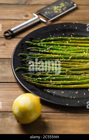 Healthy food lemon asparagus. Eating healthy food is easy with this homemade vegan dish; roasted asparagus with lemon zest on top. The veggies are ser Stock Photo