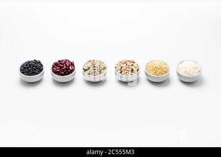 Types of rice and beans in bowls. Various uncooked staple food ingredients like chickpeas, red kidney beans, green lentils, black turtle beans, jasmin Stock Photo