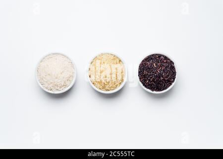 Rice bowls top view white background. 3 varieties of rice, white jasmin, basmati and black rice in white bowls on white background with copy space. Ri Stock Photo